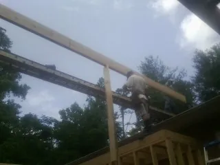 Carpenter setting a ridge beam over a new addition frame — Ice Dam Removal by Roofing Brothers in Barnum