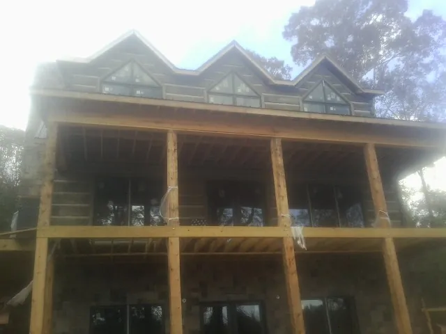 Dormers and porch framing on a large log home under construction — Roof Coating work by our crew in Barnum