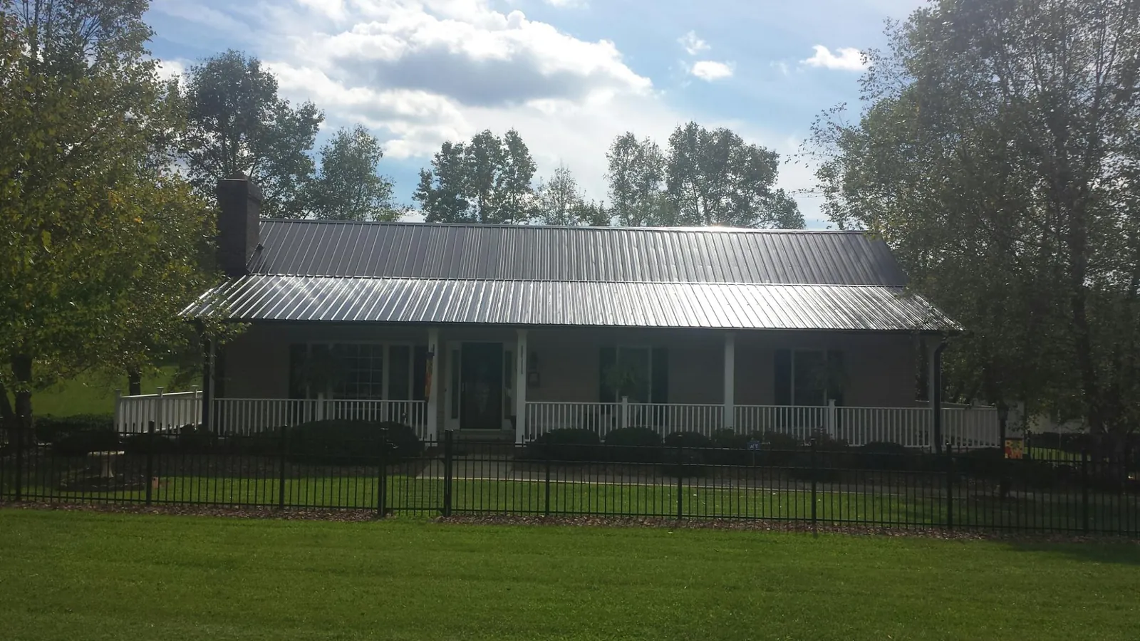 Gray metal roof on a brick ranch with a full width front porch — Gutter Guard Installation work by our crew in Barnum