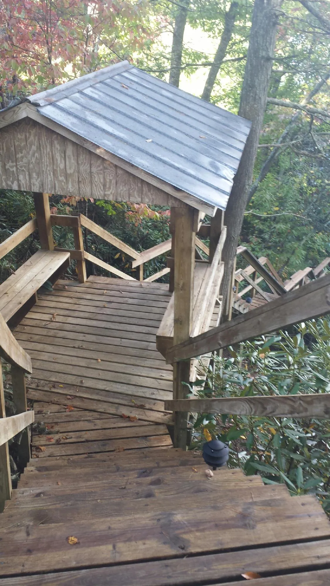 Metal roofed shelter over wooden steps on a wooded walkway — Skylight Repair & Installation work by our crew in Barnum