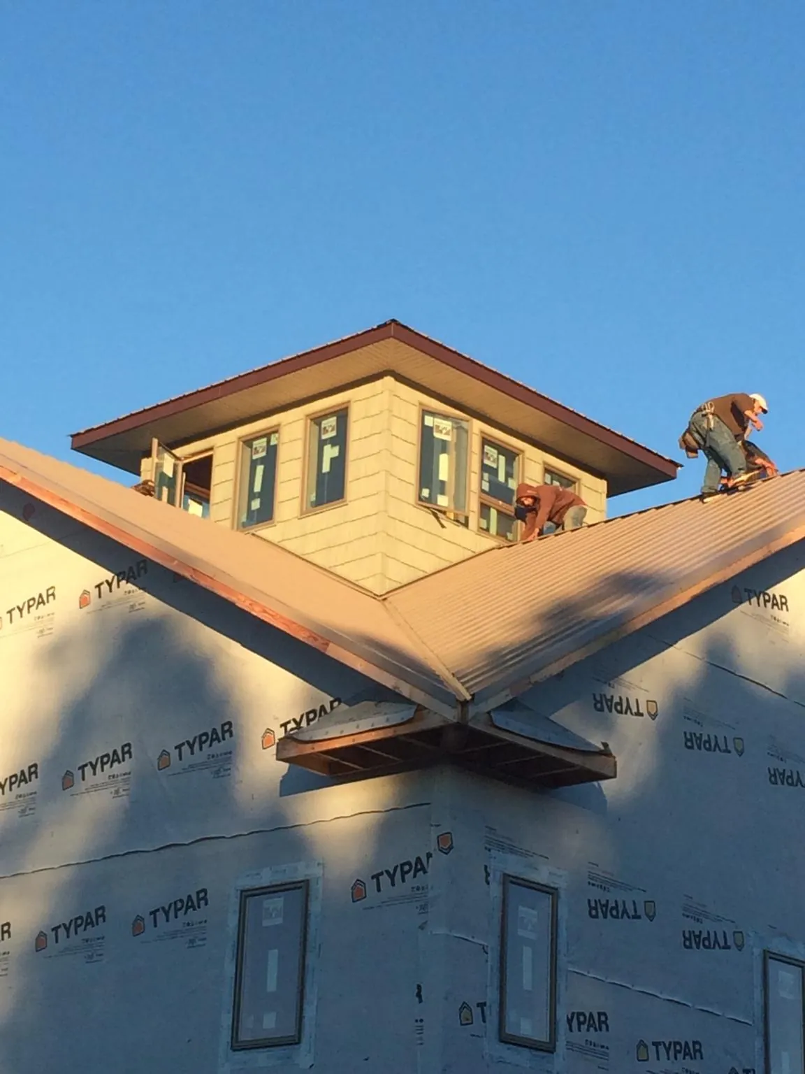Roofers working around a rooftop cupola on a new metal roof at sunset — Roof Waterproofing in Barnum by Roofing Brothers